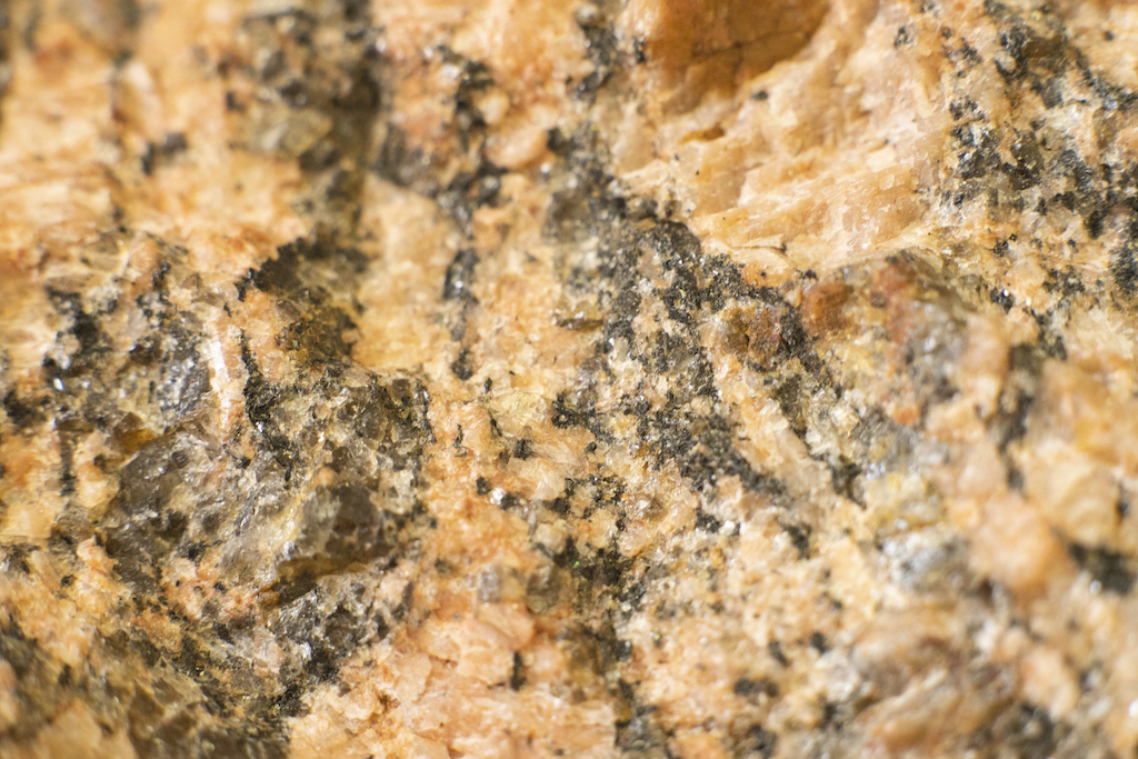 A sample of granite, a common metamorphic rock, is rich with pink feldspar minerals, an easily eroded precursor to clay minerals.