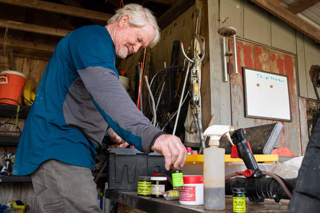 Vest looks through his collection of lure scents in Stewart, Ohio, on March 31, 2022. Scents such as coyote urine and skunk essence have become common place for Vest over the years. Vest says he and his trapping friends were easily identifiable in high school because of the scents. “I think [people] smelled us.” He says with a laugh “We usually had mud on our boots, and, depending on what you got into, you might have smelled like a fox or something.” 