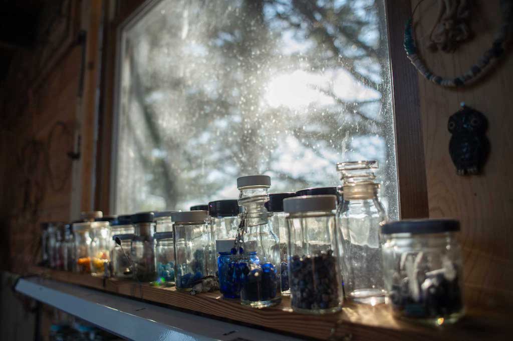 Quinn’s collection of antique beads catches light through the window of her workshop in The Plains, Ohio, on Feb. 8, 2022. Quinn’s dedication to keeping her materials sustainable does not exclude the beads she uses. “I exclusively use antique beads, mostly antique glass beads,” she says.  