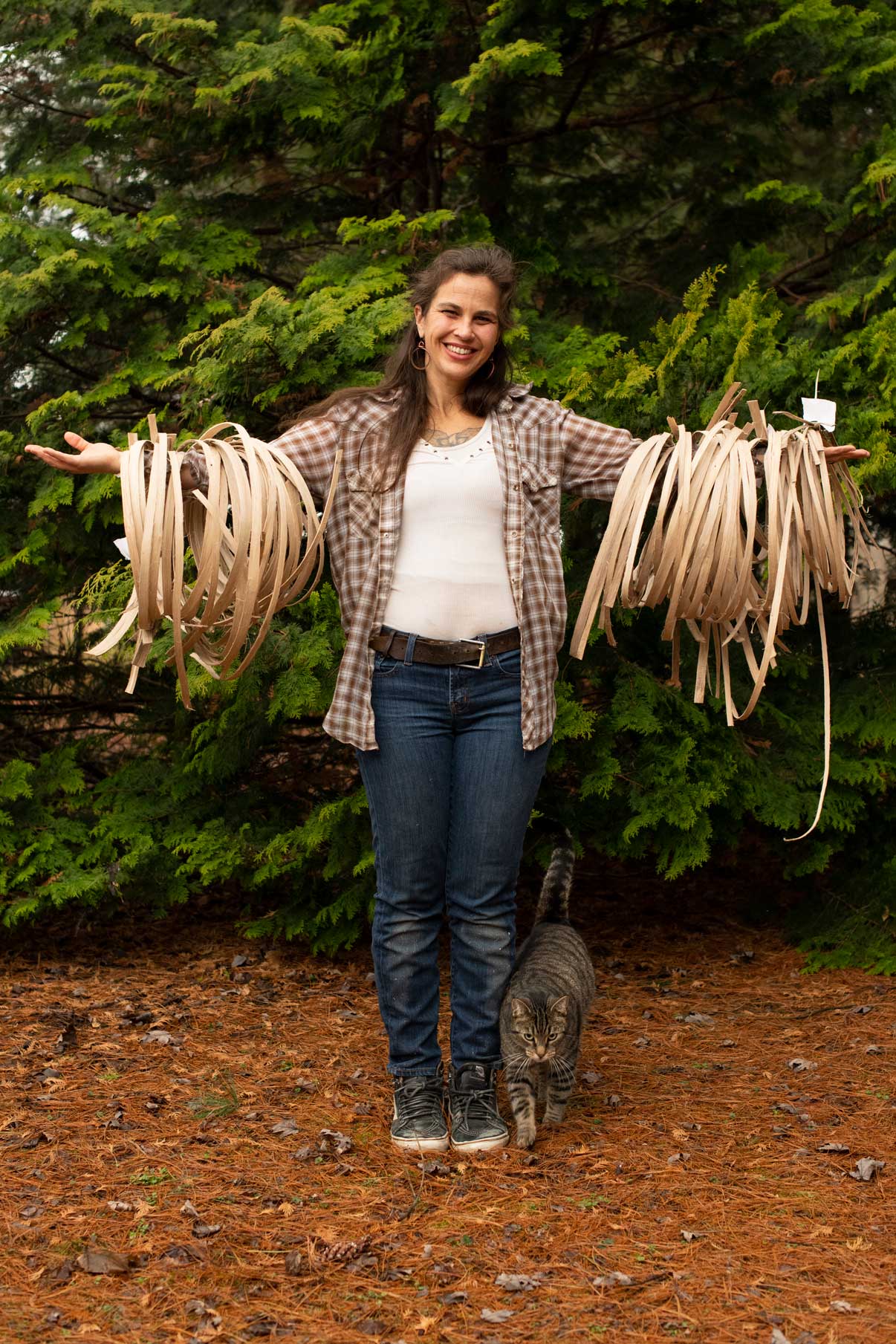 Quinn showcases her prepared basket weaving material with her cat Stripe at her feet in The Plains, Ohio, on Feb. 22, 2022.  