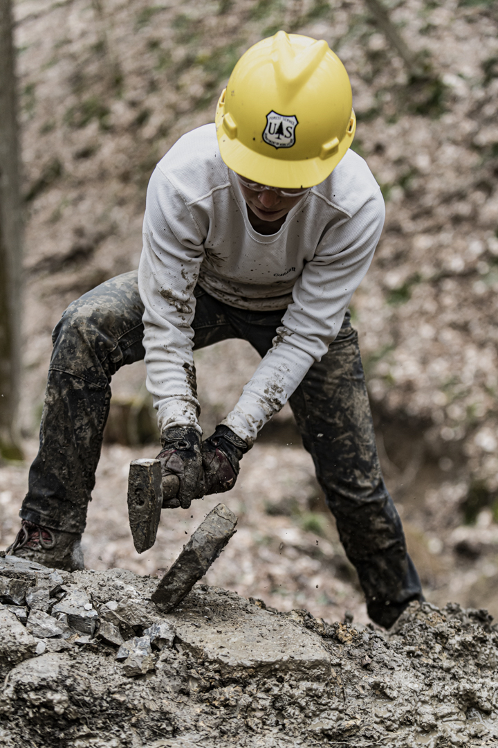 Elle Dickerman, Sustainable Recreation Manager with Americorps, works on breaking rocks as part of armoring a trail in the Wayne National Forest.  